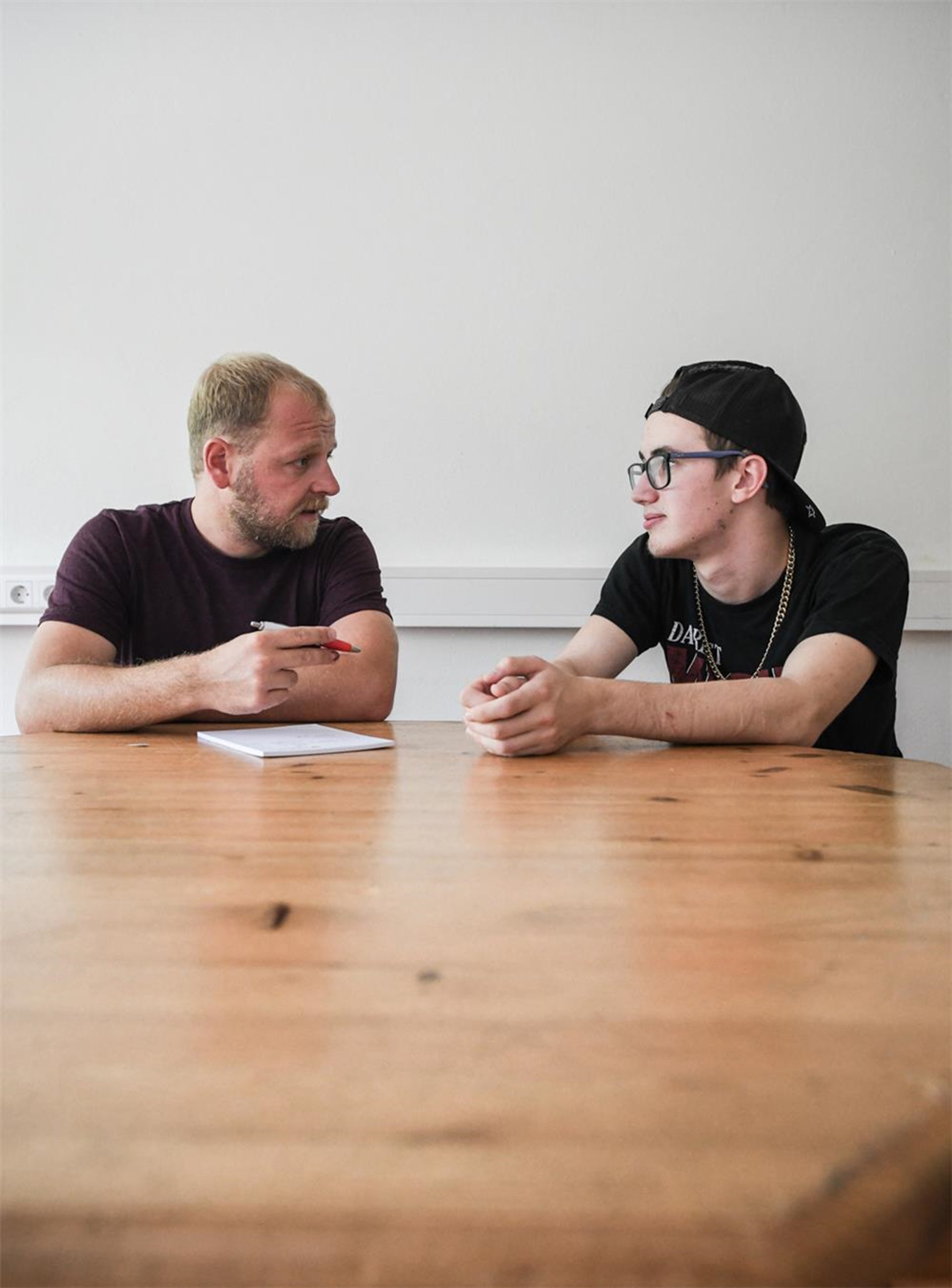 Zwei Männer sitzen am Tisch und reden miteinander